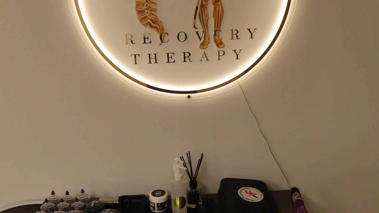 Het verlichte ronde wandbord met Recovery Therapy, met de cupping-set op het dressoir eronder